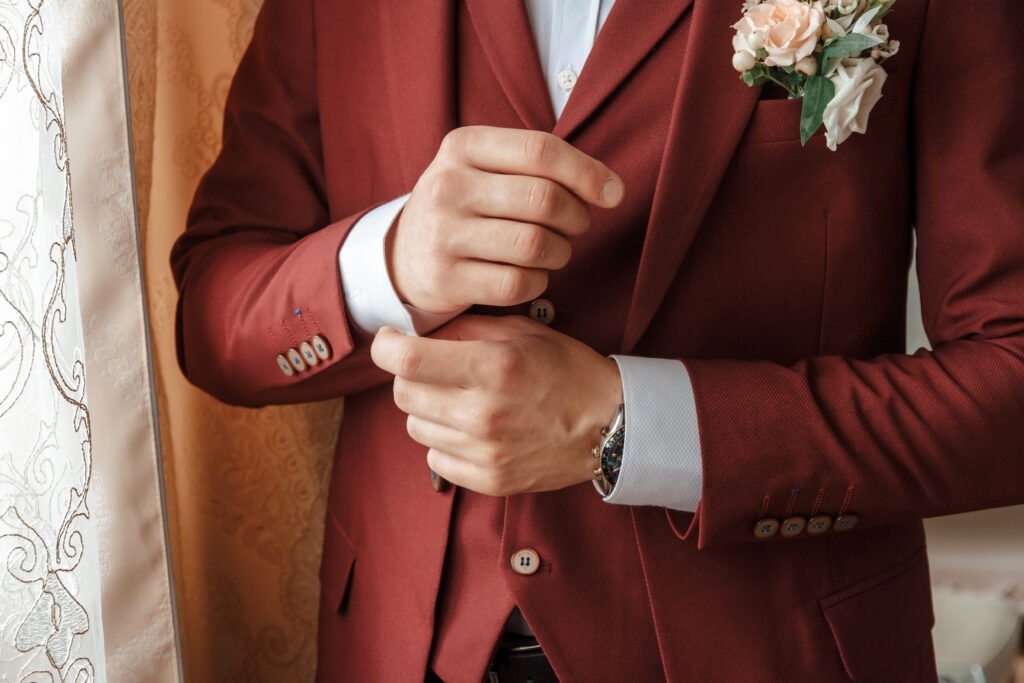 closeup of a groom in maroon suit correcting a sle utc