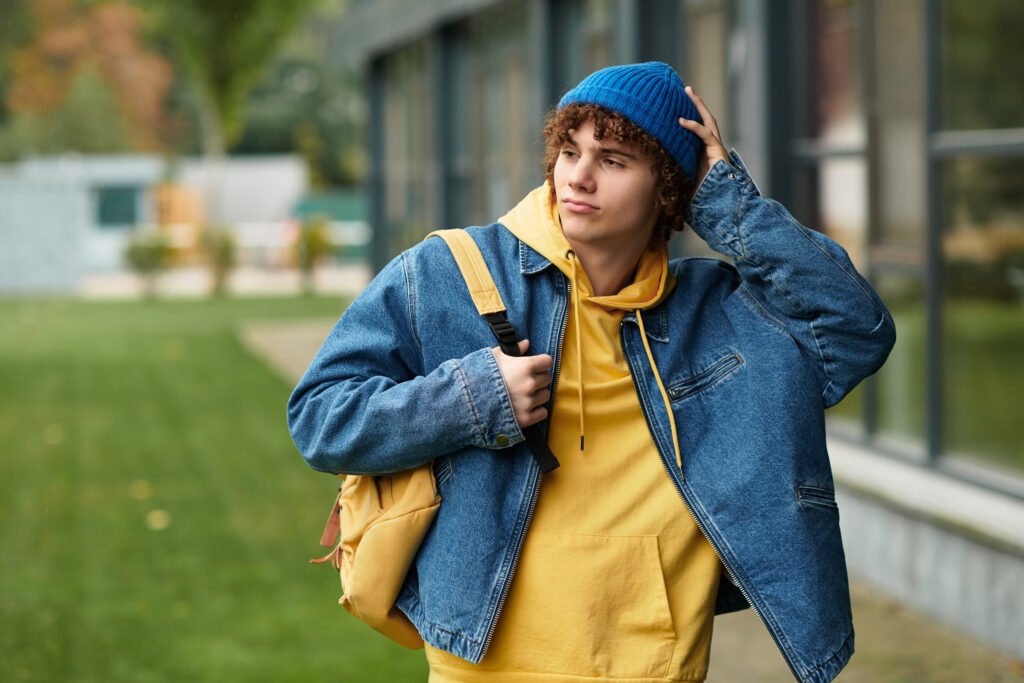curly haired teenager wearing a blue beanie and de utc