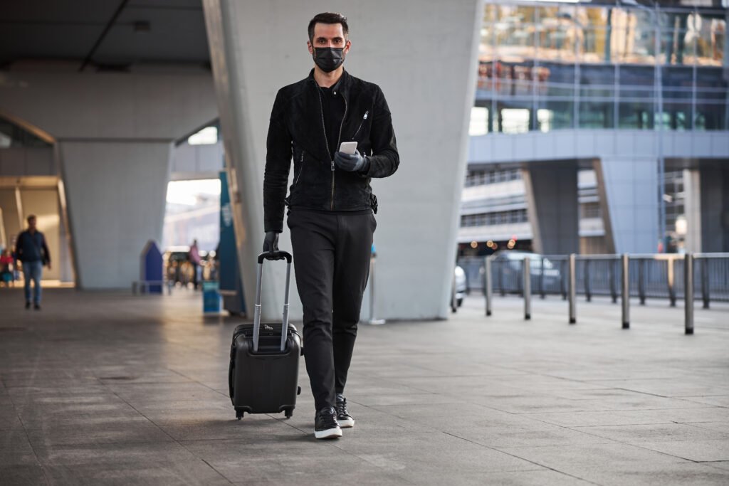 male tourist walking with luggage during the pande utc