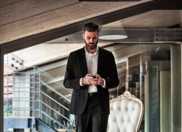 Mid adult man wearing suit holding smartphone looking down