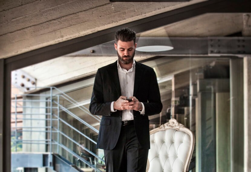 Mid adult man wearing suit holding smartphone looking down