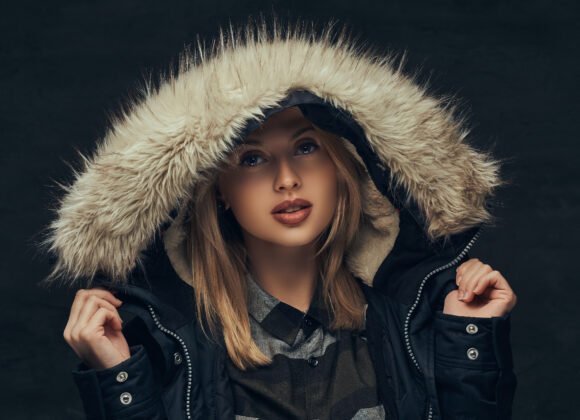 portrait sensual blonde girl winter jacket fur hood standing studio isolated dark background