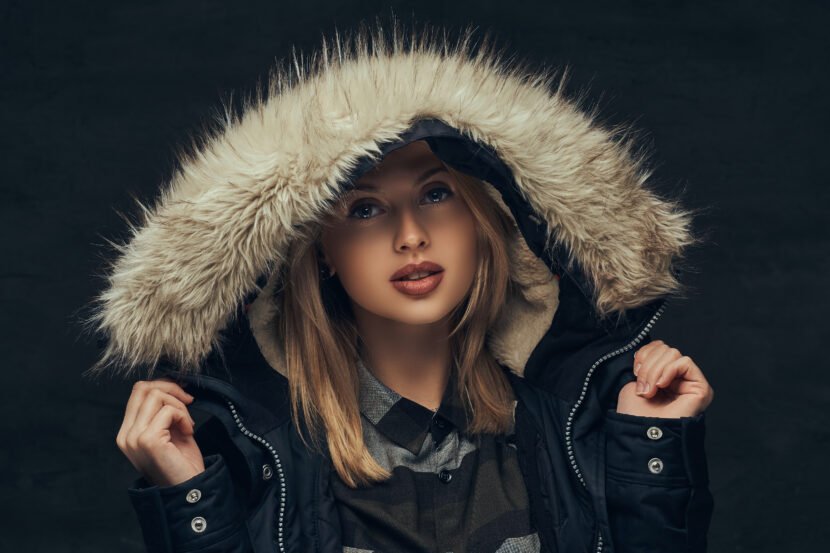 portrait sensual blonde girl winter jacket fur hood standing studio isolated dark background